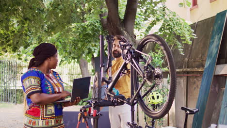 couple using laptop to repair bike wheel