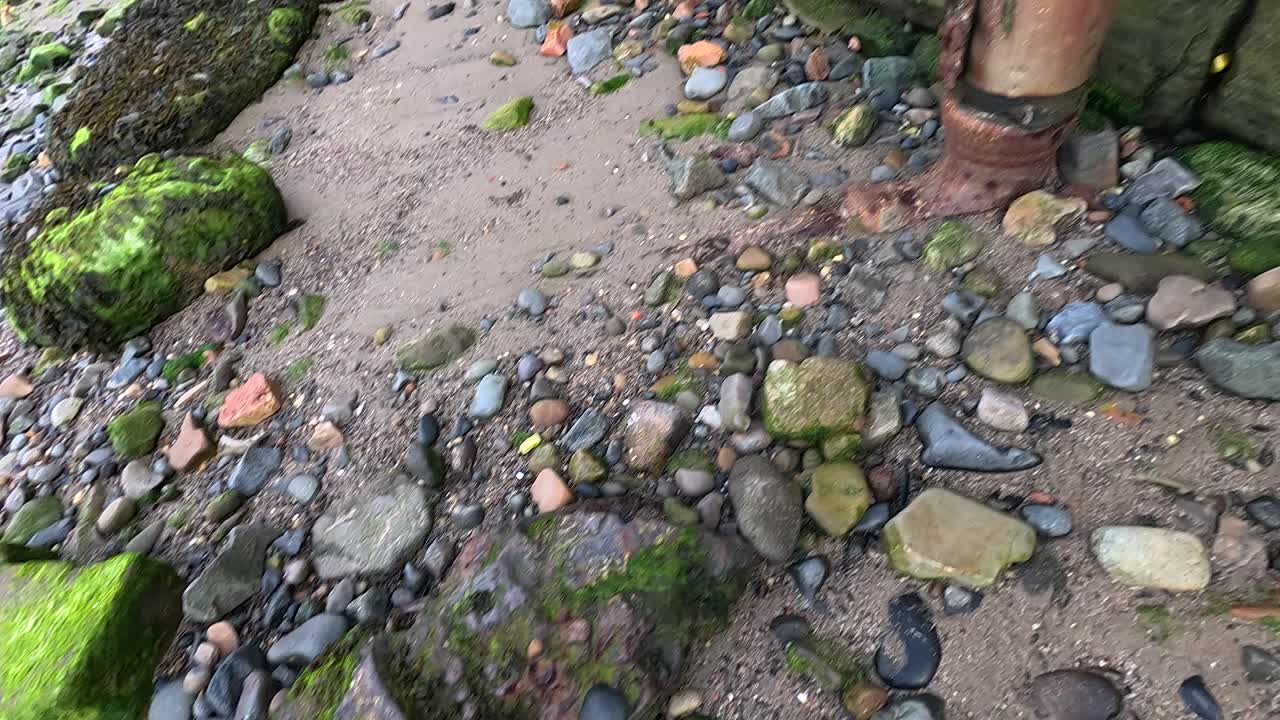 Rusty pipe against mossy stones and brick wall