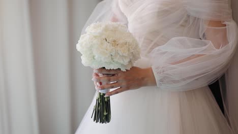 Close-up-of-a-bride-holding-flowers-in-bedroom