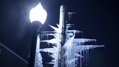 illuminated ice formation on street lamp at night: a frozen marvel with intricate icicles glimmering under streetlight's soft glow