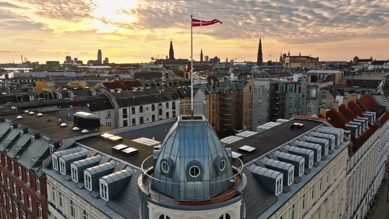 Aerial drone view of the Danish flag waving on top of a building in Copenhagen