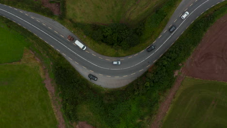 Aerial-birds-eye-overhead-top-down-view-of-cars-passing-turns-on-road-in-countryside.-Ireland