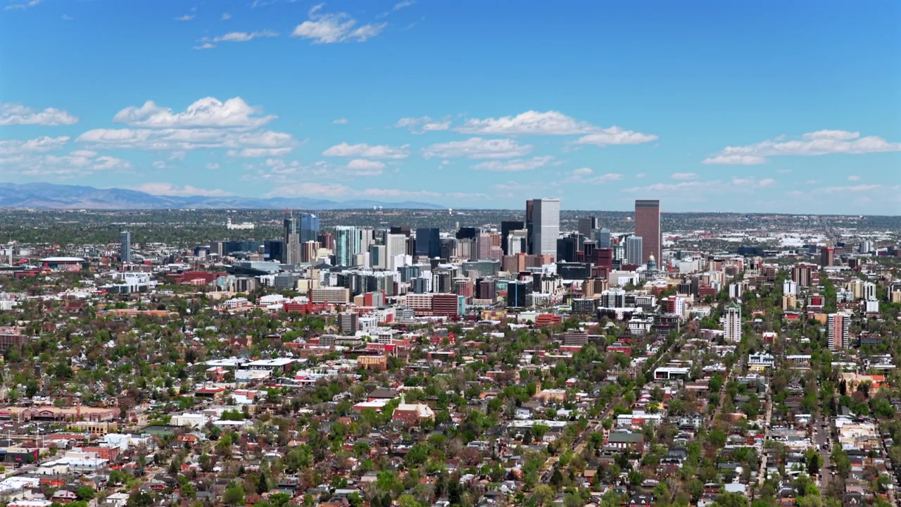 Luftdroneoptagelse af Denver bymidte og S Broadway en solrig forårs- eller sommermorgen, med skyskraberbygninger, Colorado bylandskab, trafik på I-25 motorvejen, Capitol Hill og Front Range, set fremad og opad.