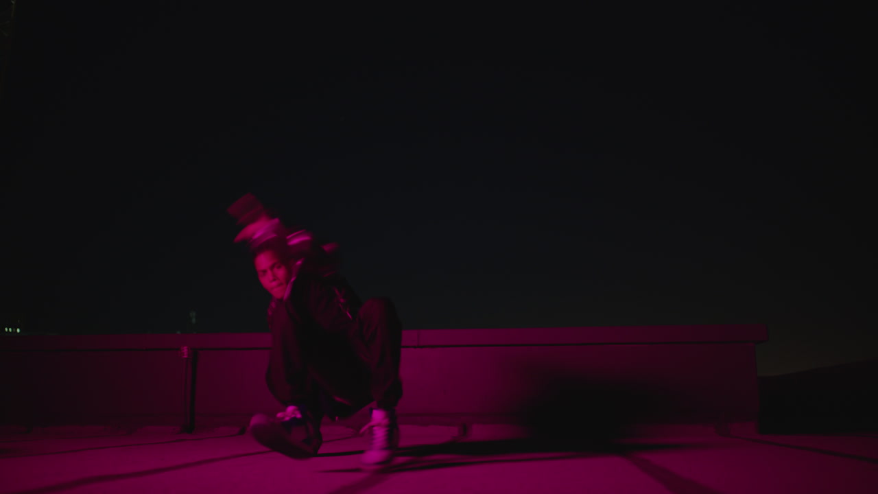 hombre bailando breakdancing en el techo por la noche bailarín de hip hop practicando rutina de baile realizando movimientos de freestyle en la ciudad con luz roja