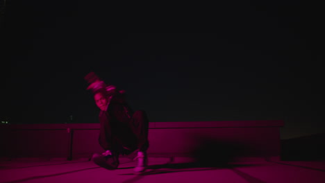 dancing man breakdancing on rooftop at night hip hop dancer practicing dance routine performing freestyle moves in city with red light