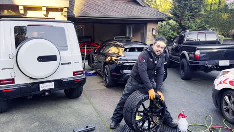 mechanic changing tire on luxury car in driveway
