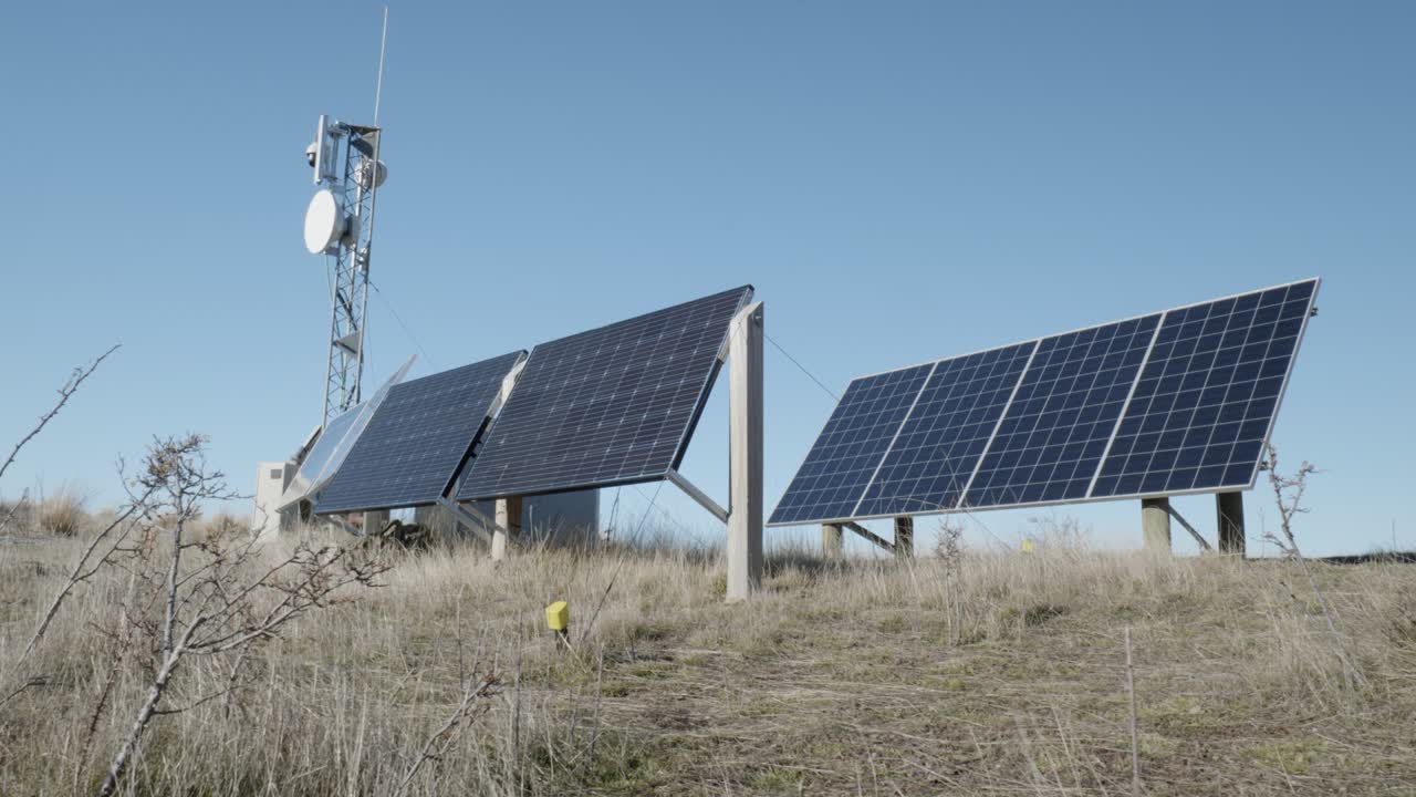 dos paneles solares y una pequeña torre de transmisión bajo un cielo despejado
