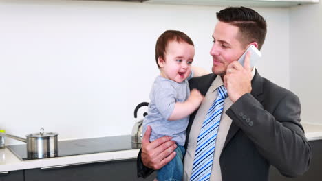 Padre-Sosteniendo-A-Su-Hijo-Antes-Del-Trabajo-Y-Hablando-Por-Teléfono