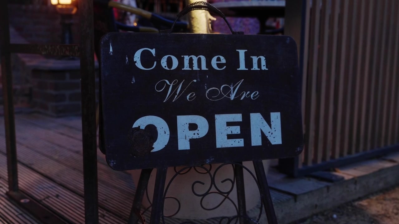 Wooden restaurant welcome sign board during blue hour, rustic entrance decor, warm evening lighting, hospitality and dining atmosphere, inviting entrance detail.