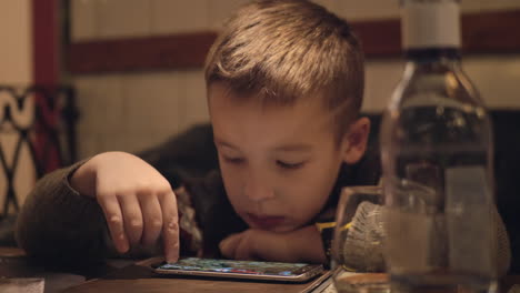 bored boy using smartphone in cafe