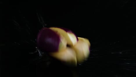 Reversed-shot-of-falling-sliced-eggplant-with-water-splash-on-black-background