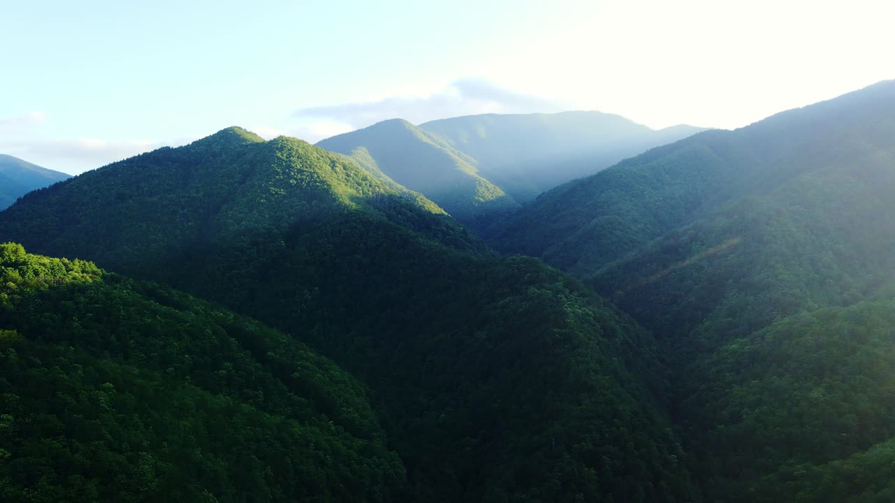 Cinematic sunset aerial over green Apennine valleys, steep forested peaks, Italy