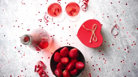 bottle of rose champagne  glasses with fresh strawberries and heart shaped gift