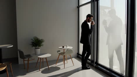 Businessman Drinks Coffee and Walks in a Modern Office