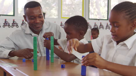 maestro ayudando a los niños de la escuela primaria a contar con bloques
