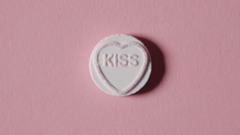 heart candy with word kiss on pink background