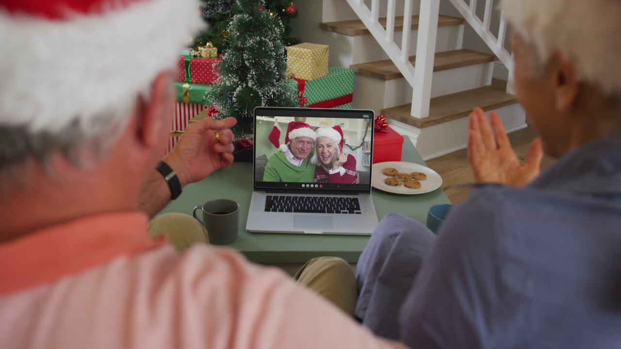 feliz pareja de ancianos caucásicos en videollamada con amigos mayores en tiempo de navidad