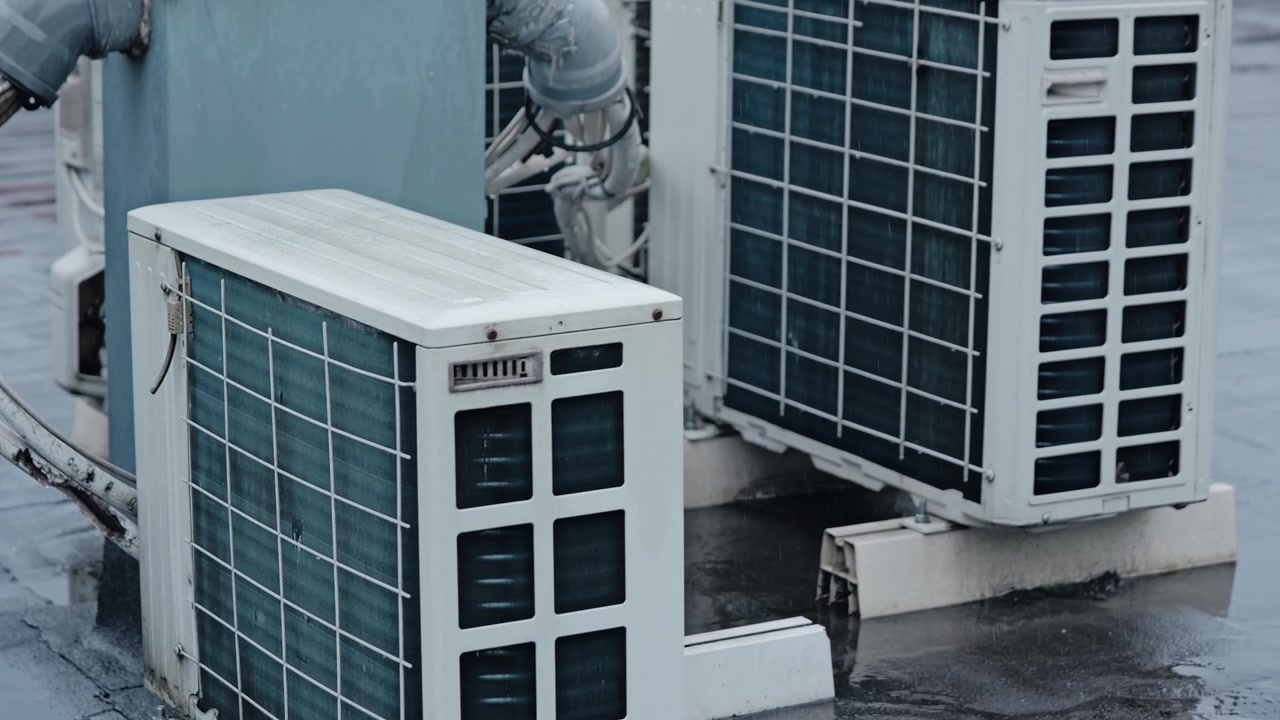 Raindrops drift past rooftop cooling systems during a cold, wet autumn daytime