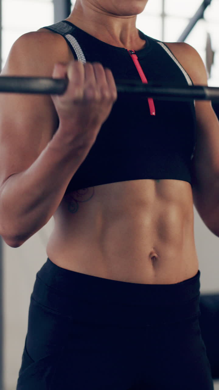 Donna forte che esegue curl bicipiti con bilanciere in palestra