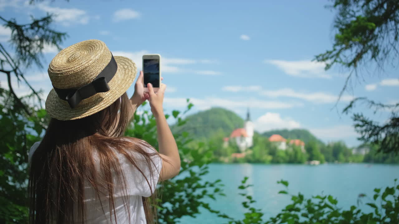 una mujer tomando una foto del lago bled.