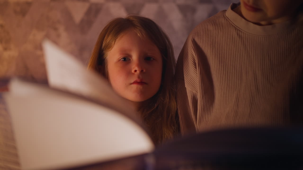 주의 깊은 소녀는 엄마가 돌린 동화 책 페이지를 봅니다.