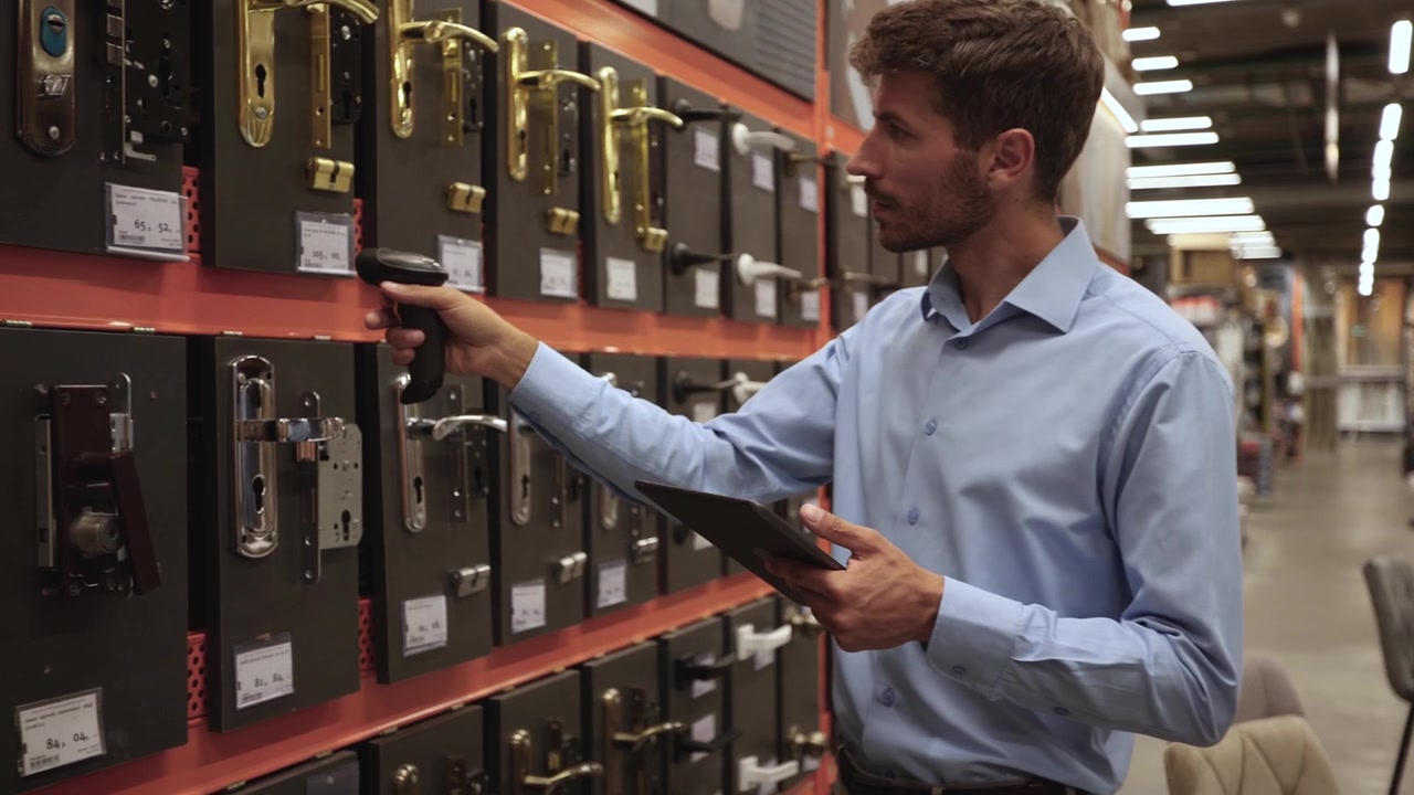 Man Scanning Door Handles with Barcode Scanner and Tablet in Hardware Store