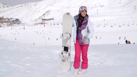 Young-woman-standing-waiting-with-her-snowboard