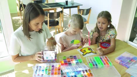 mother and daughters making pixel art with beads