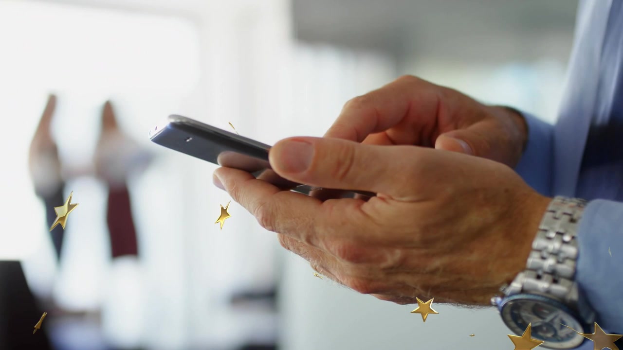 Uomo che tocca lo schermo del telefono in ufficio, facendo partire coriandoli a forma di stella dorata per celebrare una vittoria di vendita