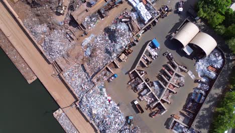 metal scrap yard, showing workers sorting and managing waste materials for recycling purposes near a city. Amazing aerial view flight drone camera pointing down