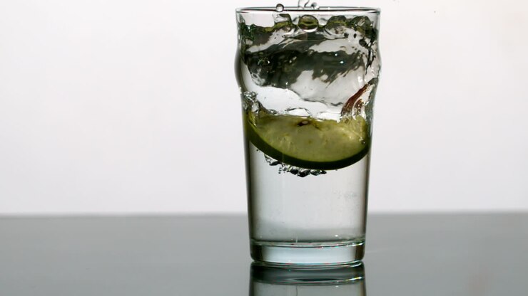 Spicchio di mela che cade in un bicchiere d'acqua