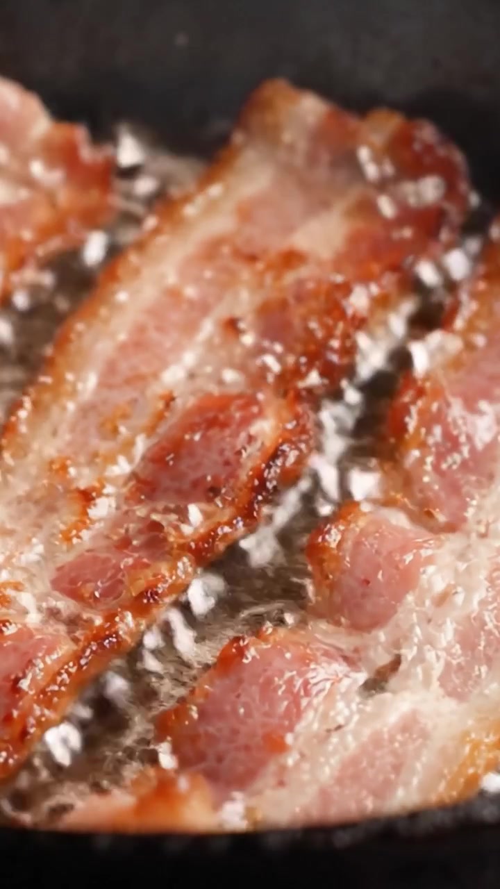 Lækkert sprødt bacon, der syder på en pande: Et nærmere kig på den mundvandsløbende proces med at tilberede perfekt stegte baconskiver.