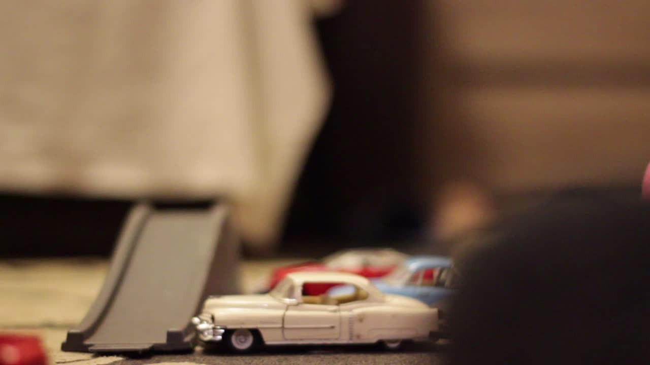 子供の子供はカーペットの上の小さなおもちゃの車で遊ぶ