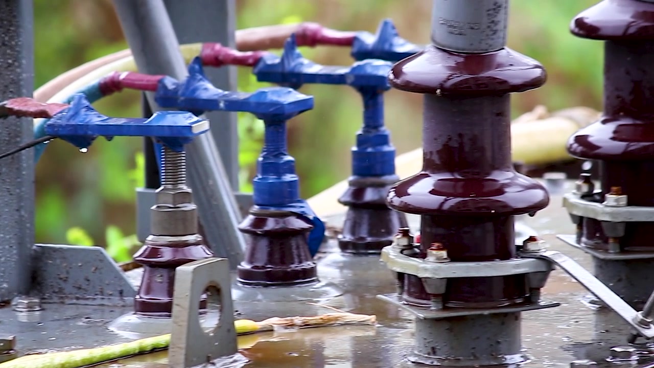 Primo piano della pioggia che cade su boccole di trasformatori ad alta tensione e connessioni elettriche. Ideale per progetti di trasmissione di energia, elettricità, infrastrutture di servizi, meteo e industria energetica.