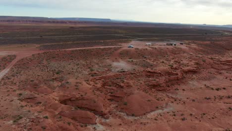 Aerial-approach-towards-van-and-cars-traveling-through-remote-desert-in-America