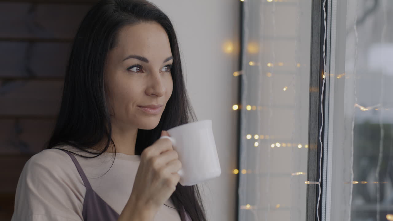 창문 에서 커피를 마시고 있는 여자