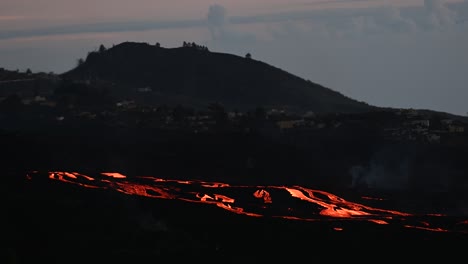 small settlement in mountainous valley with erupting volcano