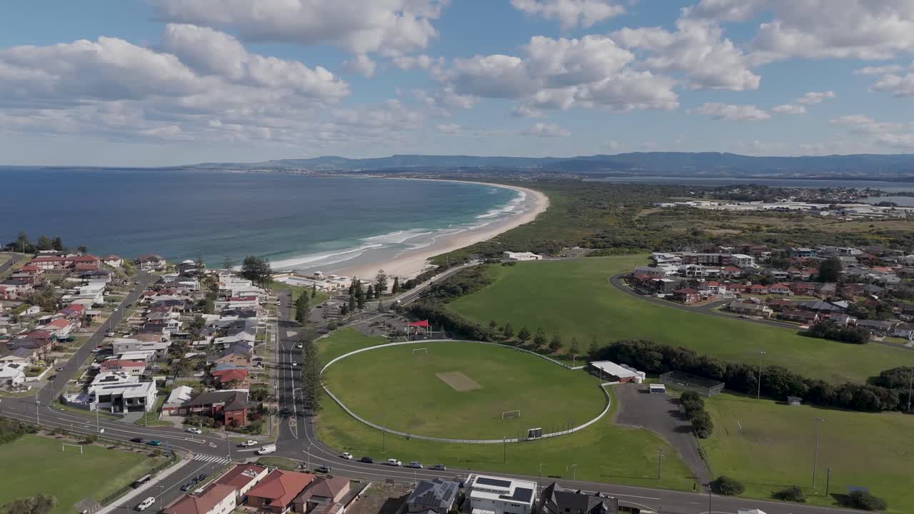 골드 코스 위의 공중 도와 놀이 구역은 포트 블라 (port kembla) 의 집과 아름다운 해변 위에 은  구름이 있습니다.