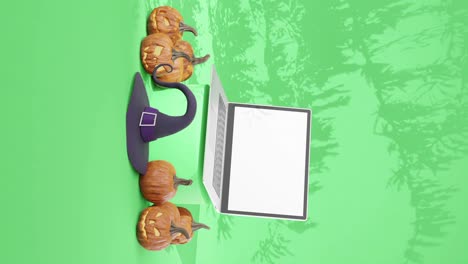 Halloween-Kürbisse-Und-Laptop-Mit-Weißem-Bildschirm-Auf-Grünem-Hintergrund,-Vertikal