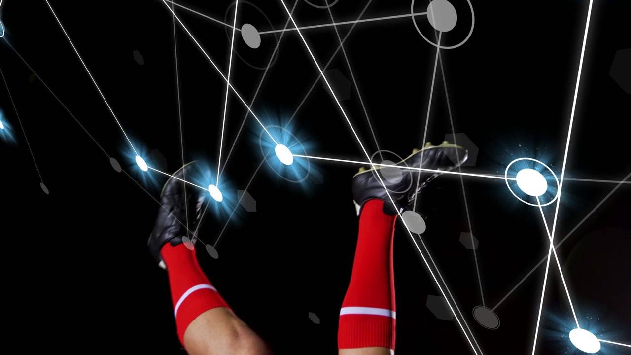 Le gambe di un giocatore maschio che toccano un pallone da calcio, eseguendo un calcio aereo, con una rete luminosa sullo sfondo.