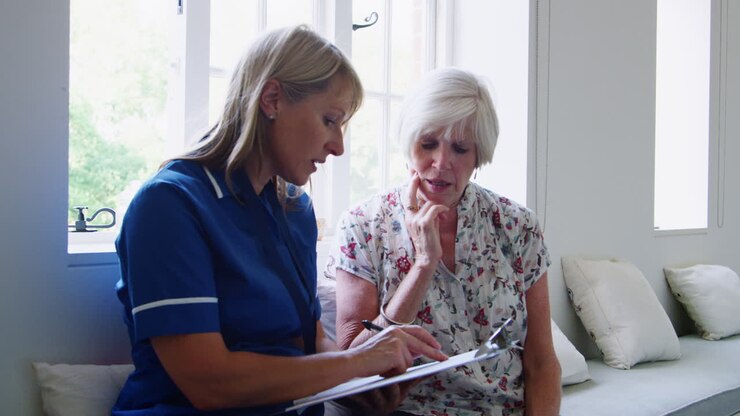 Nurse sits doing a questionnaire with a senior woman