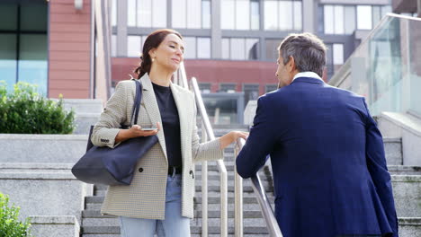 businessman and businesswoman meeting outdoors standing on steps and talking