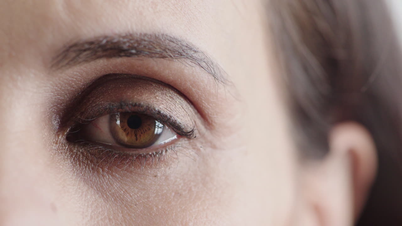 ojo de mujer de cerca mirando a su alrededor pensativo usando maquillaje cosméticos belleza femenina