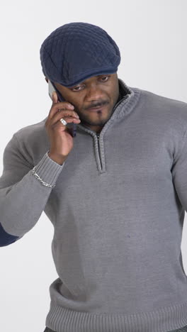african businessman with a phone. portrait of a sportsman with dark skin standing in studio and talking seriously on the mobile phone. copy space. vertical video