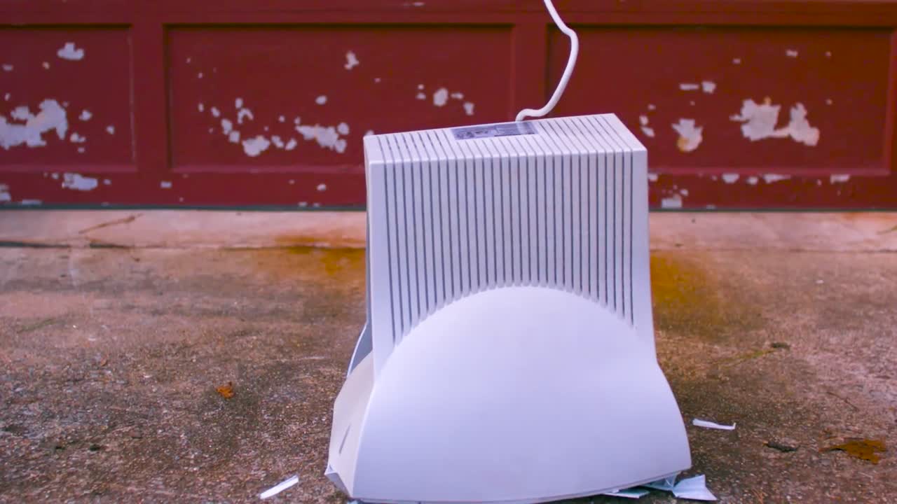 오래된 색 컴퓨터 모니터가 던져지고 바닥으로 떨어지고 느린 움직임으로 조각으로 부서집니다.