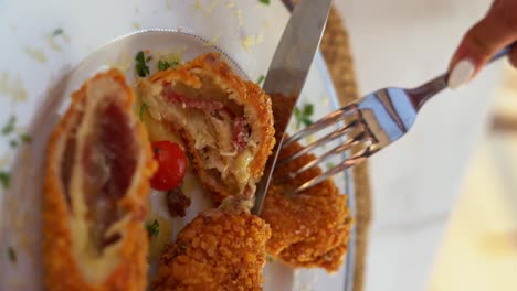 a woman eat her plate that contains a delicious cordon bleu, close up shot, high angle shot, vertical video