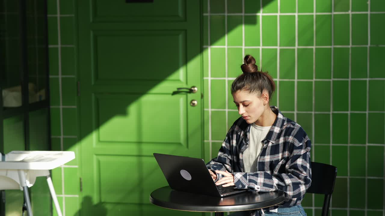mujer joven trabajando en una computadora portátil en un café al aire libre