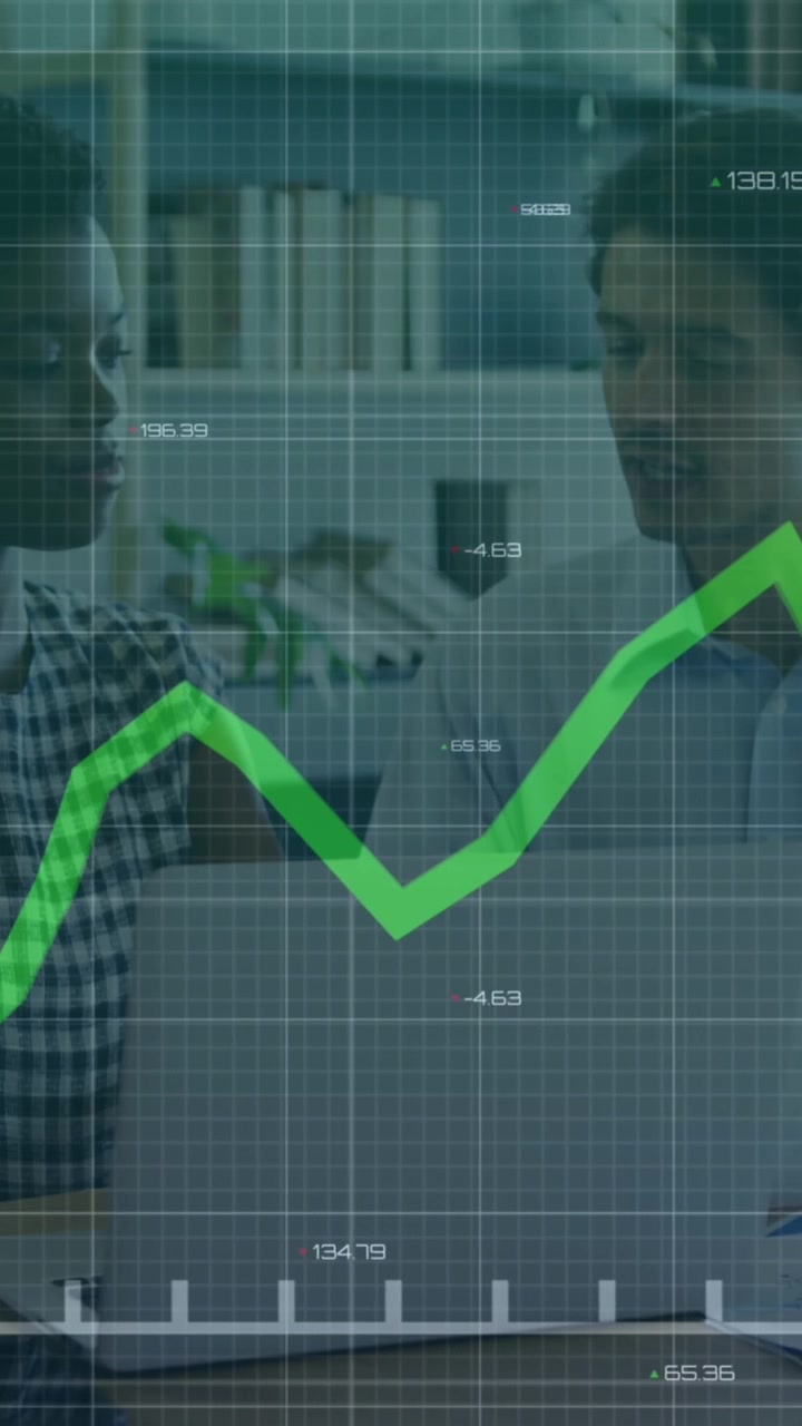 Animazione di un grafico a linee e numeri variabili, sovrapposti a colleghi di diverse etnie che discutono davanti a un portatile.