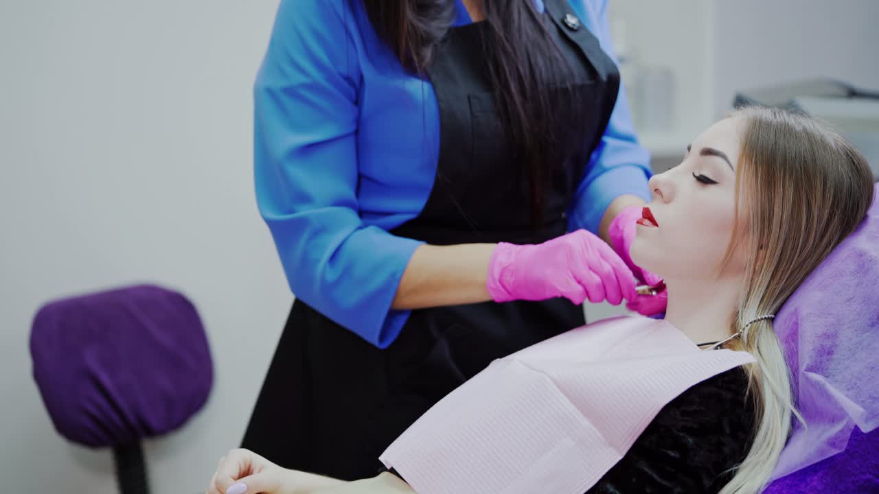 Young woman in a beauty salon. Beautician prepares female patient before the tattoo procedure. Cosmetology concept.