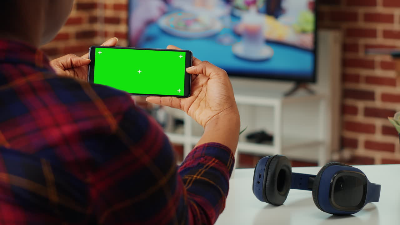 Office employee looking at horizontal greenscreen on smartphone